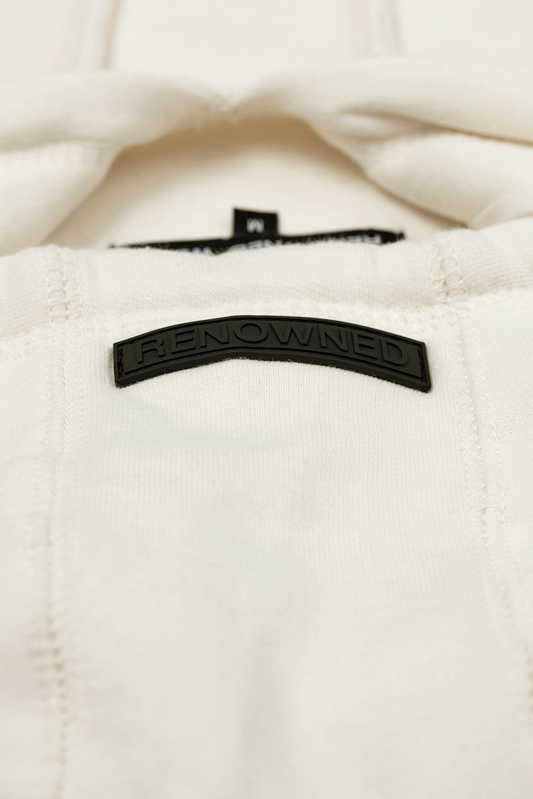 Rubber Label Detail of the Cream Colored Premium 400gsm Heavyweight Hoodie by RENOWNED WEAR