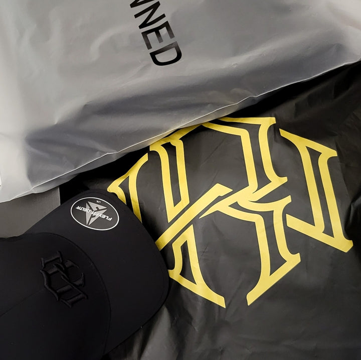 Display of RENOWNED WEAR Brand packages alongside a stylish RW Black Monogram Motif Cap.