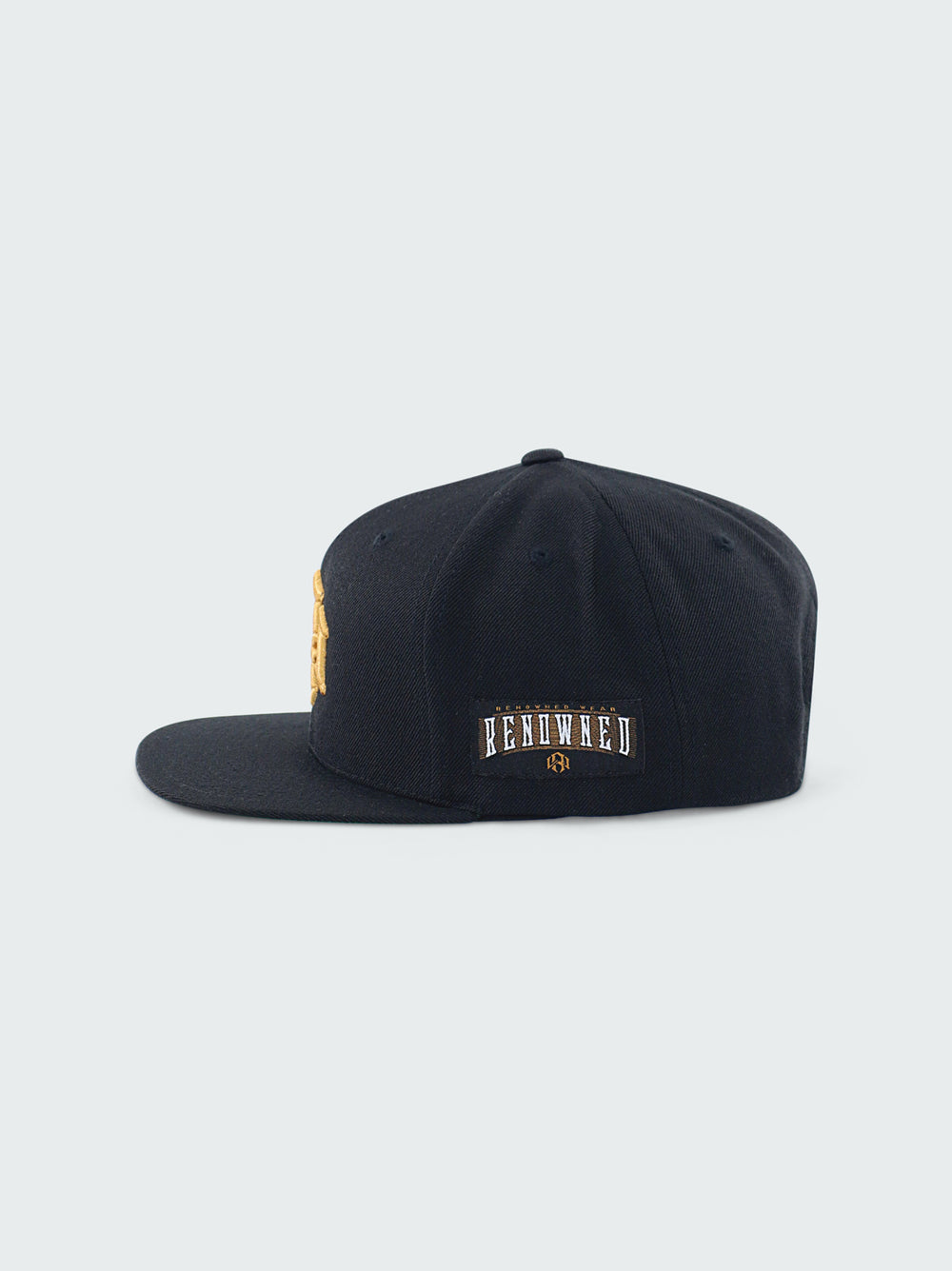 Black Snapback Cap by RENOWNED WEAR featuring a Gold 3D Embroidered front logo left side woven patch